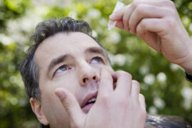 man applying eye drops
