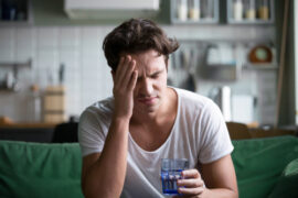 man holding a glass of water having a headache