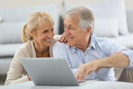 old couple smiling while using computer