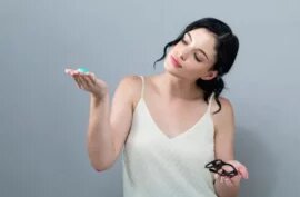 young woman choosing between contact lense and eye glasses