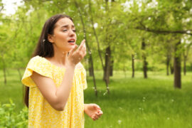 young woman suffering from seasonal allergy outdoors